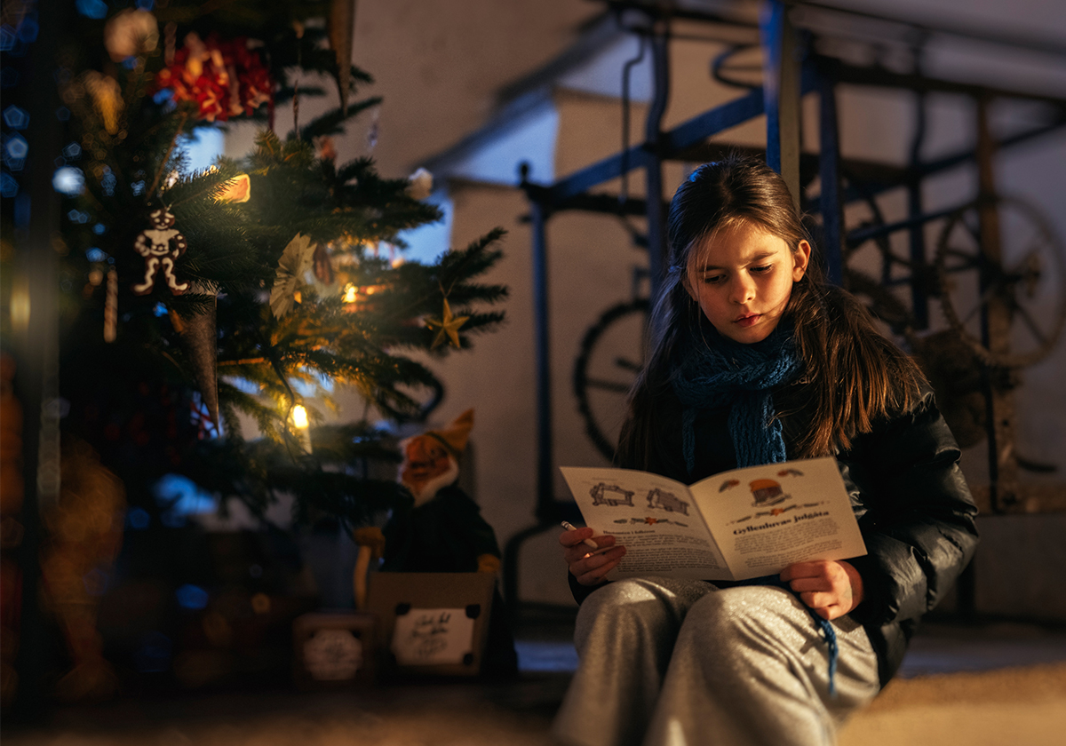 Barn sitter vid gran och läser broschyr