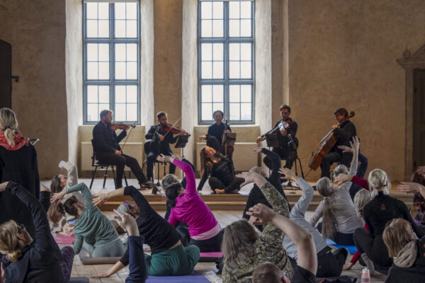 Grupp gör yoga framför orkester